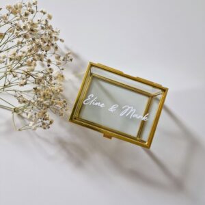 Glazen ringdoosje met goudkleurige details bestickerd met namen Eline en Mark in witte tekst.